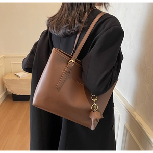 Detail view of brown PU leather tote bag with unique elephant charm on the shoulder strap