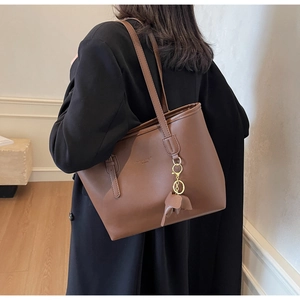 Close-up of vintage brown PU leather tote bag with cute elephant charm and gold lettering