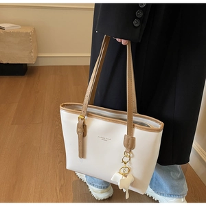 Close-up of white PU leather tote bag with brown straps and cute elephant charm