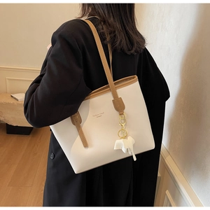 Detail of white minimalist tote bag with elephant charm and Fashion Trend print