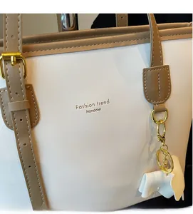 Detail of cream faux leather tote bag with brown strap and golden horse pendant