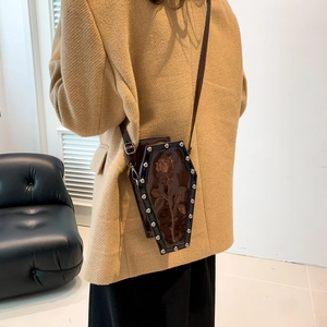 Dark brown coffin-shaped crossbody bag with rose relief and silver studs on model