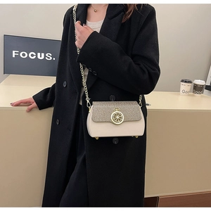 Dettaglio della borsa a catena bianco panna con patta glitterata e chiusura dorata su cappotto
