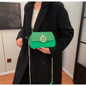 Dettaglio borsa a catena verde brillante con fibbia a corona su cappotto nero