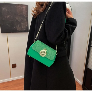Dettaglio borsa a catena verde con fibbia a corona dorata e texture glitterata su modella