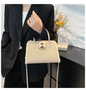 Detailansicht beige matte Tasche mit weißem Lammfellbesatz und goldenen Beschlägen