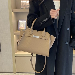 Elegant earth-tone pebbled leather tote bag with metallic twist lock in a home setting