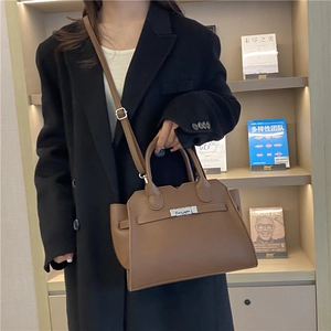 Brown textured leather handbag with top handles and silver clasp shown in lifestyle setting