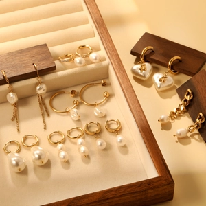 Boucles d'oreilles en acier doré 18K avec perles et cristaux sur un présentoir à bijoux
