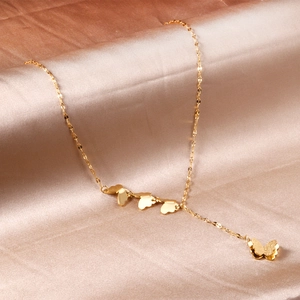Elegante goldene Schmetterlingskette mit Quastenanhänger auf champagnerfarbenem Seidenstoff