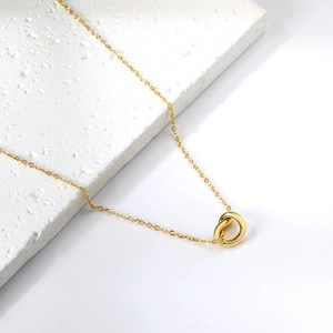 18K gold plated stainless steel bowknot necklace displayed on a white marble stone base