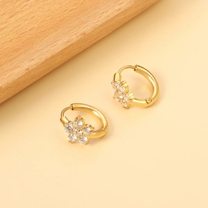 Détail d'une boucle d'oreille fleurie dorée sertie de zircons clairs scintillants