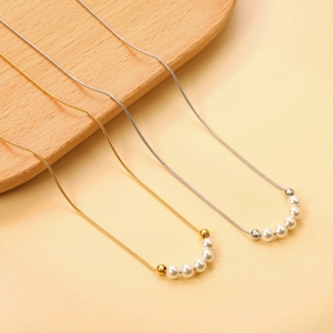 Detailed view of gold and silver snake chain necklaces with white round pearls
