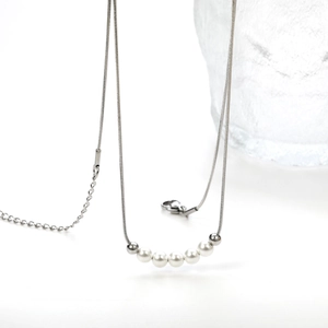 Macro shot of silver snake chain with five white pearls and adjustable lobster clasp