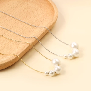 Detail view of gold and silver box chains with four graduated white pearls in a curved row