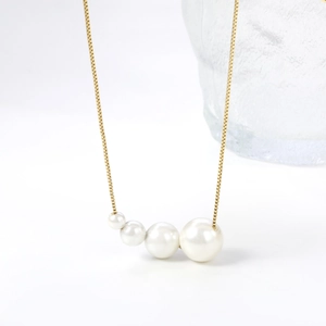 Elegant gold box chain necklace featuring four gradient white pearls on white background