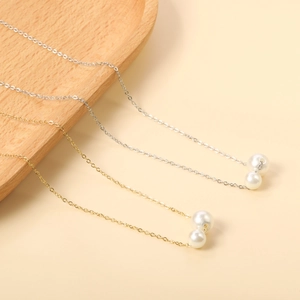Detail of silver and gold stainless steel necklaces with double white pearl pendants