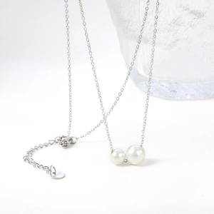 Detailed macro view of the double pearl pendant and the s.steel engraving on the chain