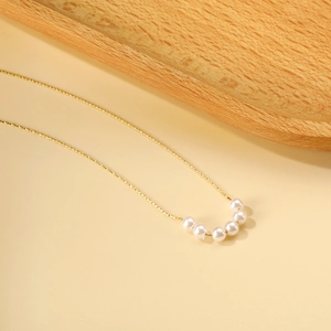 Macro detail of minimalist gold chain necklace featuring six elegant white round pearls