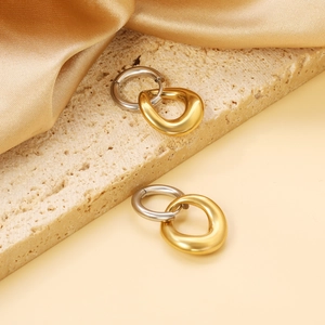 Boucles d'oreilles minimalistes entrelacées argent et or sur surface en pierre