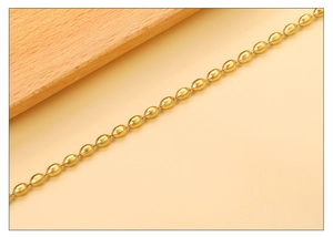 Macro shot of gold-plated olive bead bracelet with smooth metallic finish and elegant link chain