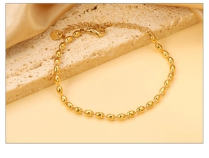 Close-up of golden stainless steel bean link bracelet with lobster clasp and extension chain