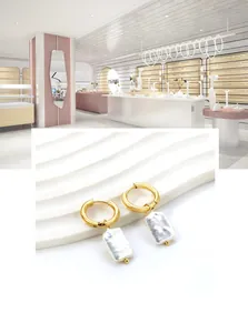 Detailed close-up of golden hoop earrings featuring rectangular white pearl pendants