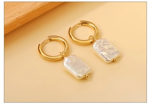 Detailed close-up of gold hoop earrings with irregular iridescent white shell pendants