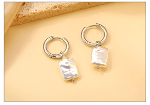 Detail of silver hoop earrings with irregular iridescent rectangular pearl pendants