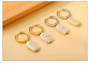 Close-up of gold and silver hoop earrings with rectangular baroque pearl pendants