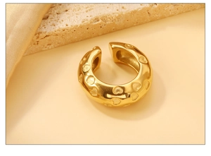 Détail macro du clip d'oreille en C plaqué or 18K avec motif de cœurs en relief