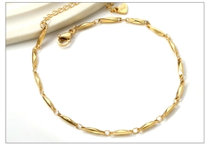 Detail of gold stainless steel anklet with segment twist links and engraved heart charm