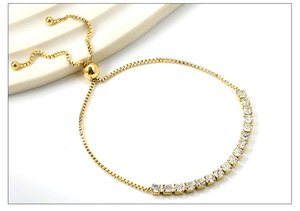 Détail du fermoir coulissant doré et des zircons blancs carrés sur le bracelet tennis