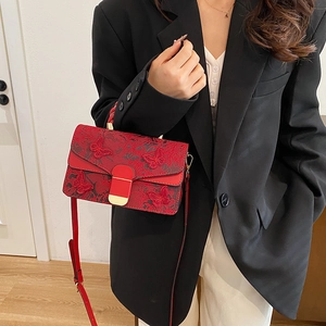 Sac rouge brodé de papillons avec poignée tressée porté par un mannequin