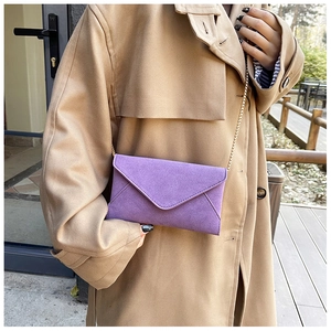 Detailed view of a purple frosted suede envelope crossbody bag with a gold chain strap