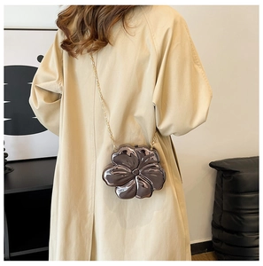 Detail of mirror-finish flower-shaped crossbody bag with golden chain strap on model