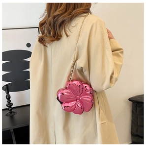 Detail of a bright pink metallic flower-shaped crossbody bag with a fine gold chain strap