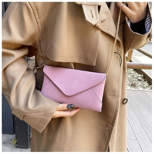 Close-up of pink frosted envelope bag with gold chain strap on a trench coat