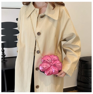 Pink metallic flower crossbody bag with gold chain strap shown on beige trench coat