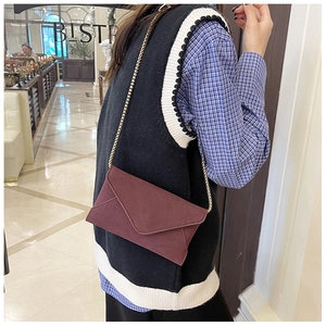 Close-up of burgundy frosted envelope crossbody bag with a slim gold chain strap