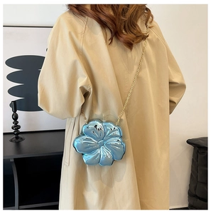 Sky blue flower-shaped crossbody bag with gold chain strap shown on a model