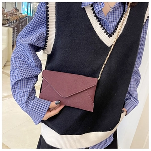 Detail of burgundy frosted envelope crossbody bag with a slim metal chain strap