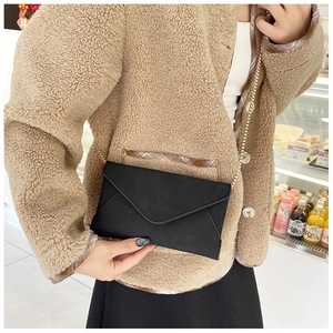 Close-up of black suede envelope crossbody bag with a refined golden chain strap