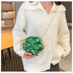 Model wearing a vibrant green flower-shaped mini crossbody bag with a sleek gold chain strap