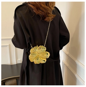Detailed view of a gold metallic flower-shaped crossbody bag with a slim chain strap
