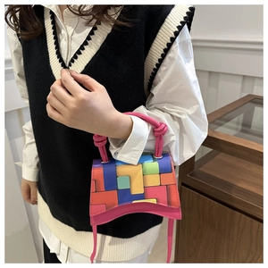Détail du mini sac multicolore avec base incurvée et poignée nouée rose sur un modèle