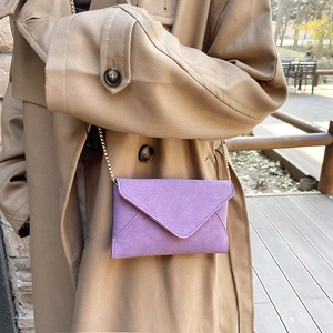 Purple suede envelope chain shoulder bag worn with a stylish khaki trench coat