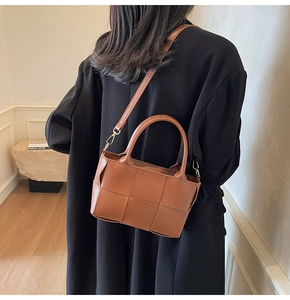 Close-up of brown woven leather handbag detail with golden hardware and strap