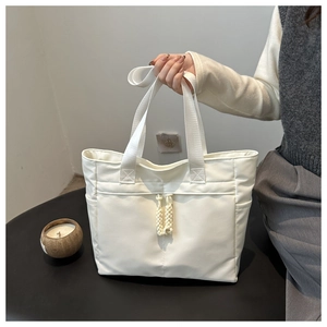 Detailed view of large white canvas tote bag featuring front drawstring pocket and side compartments