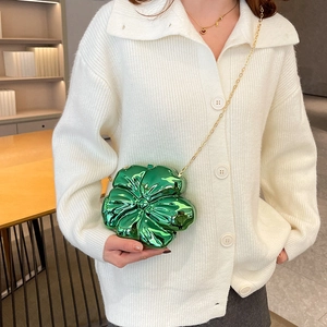 Chic green flower mini bag with metallic finish and gold chain strap on white knit top